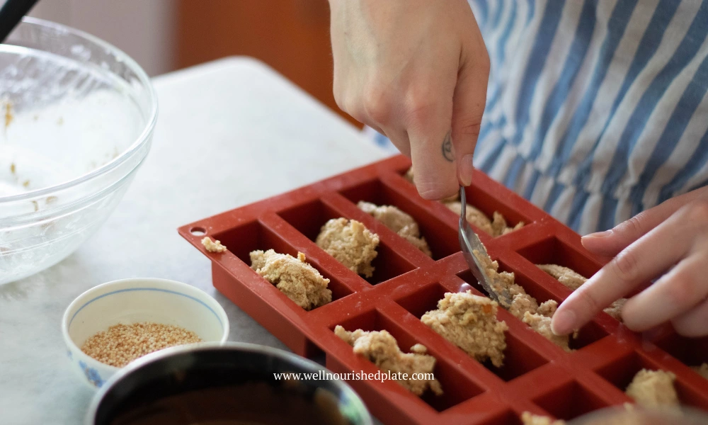 Woman pressing the oatmeal bar base into chocolate molds