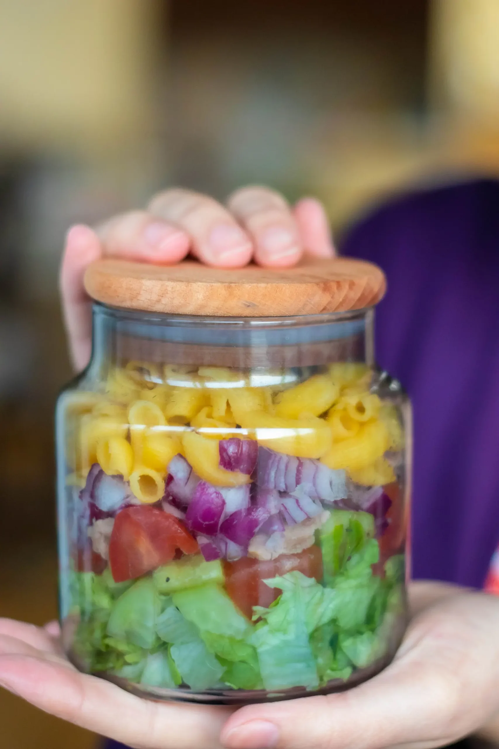 Girl holding a mason jar with cold tuna pasta salad