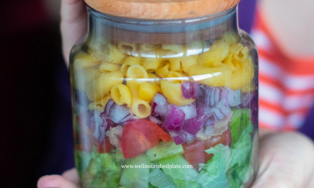 woman holding a gluten free pasta salad in a jar
