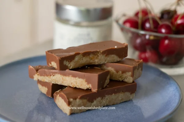 Healthy peanut butter oatmeal bars on a plate next to cherries