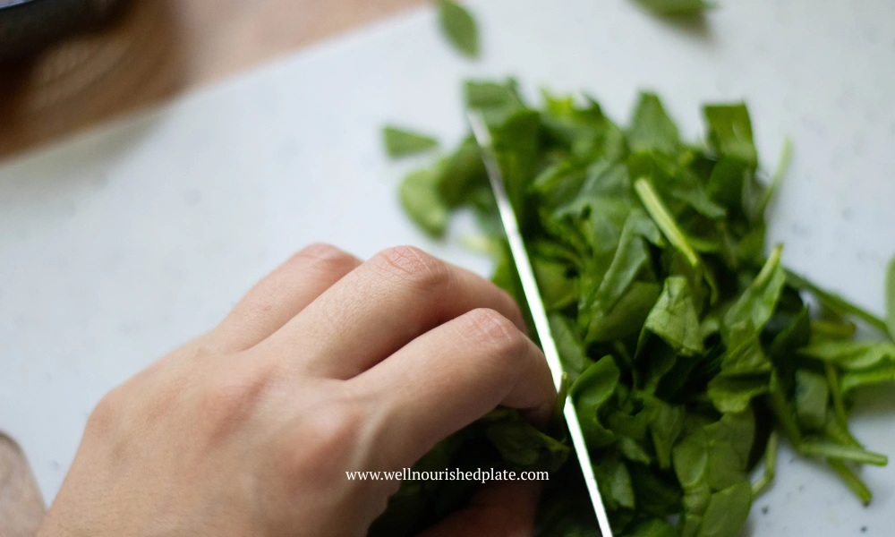 woman chopping spinach on a board