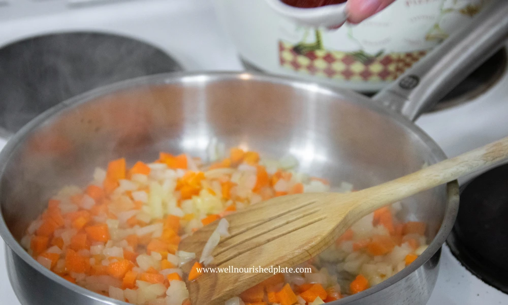 frying onion and carrots in a stainless steel pan